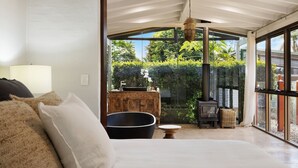 Ein modernes Interieur mit einem großen Fenster, einem Holzschrank, einer schwarzen Badewanne und einer hängenden Leuchte.