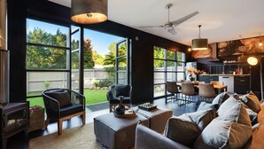 A spacious living area with large windows, a dining set, and a kitchen. - Glenbrook Guest House (Ewingsdale)