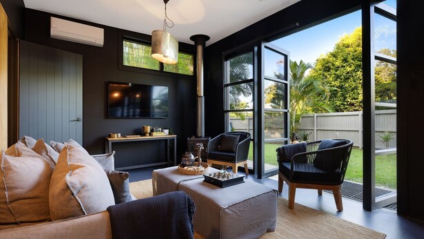 A modern living room with a TV, sofa, chairs, and a fireplace. - Glenbrook Guest House (Ewingsdale)