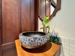 A bathroom with a round vessel sink, a wooden vanity, a green bottle, and a mirror. - 75 Nam Ngu (Hanoi)