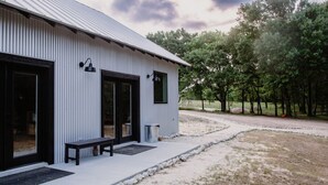 A single-story building with a corrugated metal roof, large glass doors, and a bench outside.