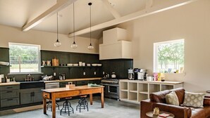 A spacious kitchen with a dining area, bar stools, and a leather couch.
