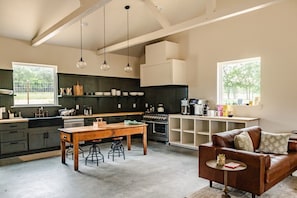 A spacious kitchen with a dining area, bar stools, and a leather couch.