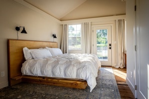 A bedroom with a wooden bed, a large window, and a door leading outside.