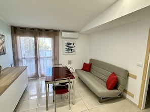 Ein gemütlicher Wohnbereich mit Esstisch, einer Couch und einem Vorhangfenster.