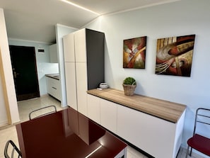 Eine moderne Küche mit weißen Schränken, einer Holz Arbeitsplatte und zwei abstrakten Gemälden.