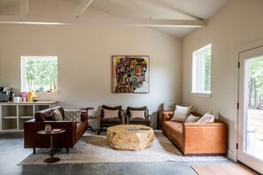 A spacious living room with a coffee table, sofas, and a large abstract painting on the wall.