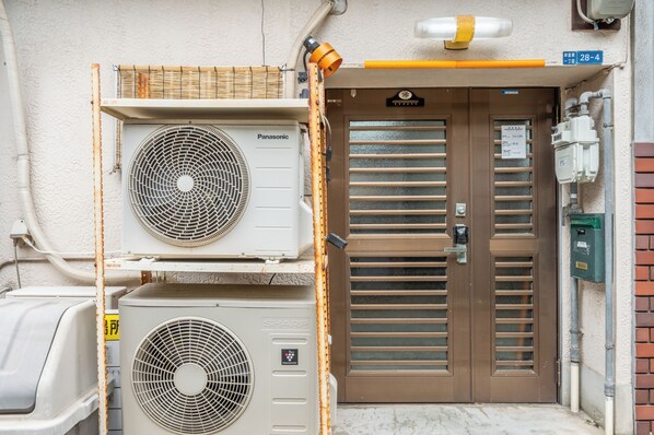 Un equipo de aire acondicionado, una puerta con un letrero y un cuadro de empalmes.