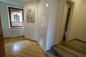 A hallway with wooden flooring, a window with a view of a building, and a staircase leading to another floor. - Riverside Ljubljanica With Parking 3 (Ljubljana)