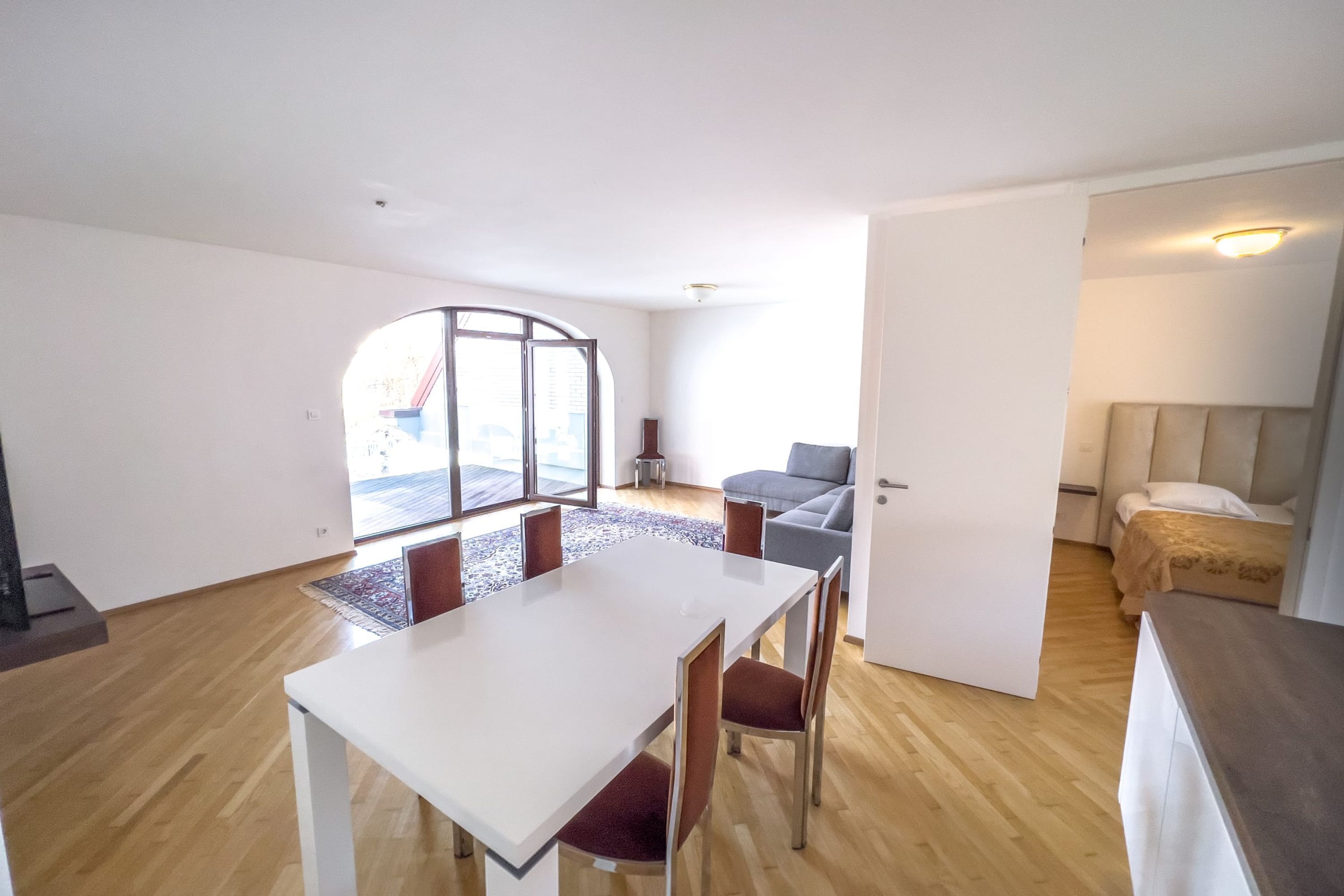 Un apartamento moderno con zona de comedor, sofá, cama y un ventanal grande.