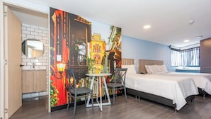 Una camera d'albergo con un letto, due comodini, un tavolino con sedie, uno specchio e un grande affresco a parete.