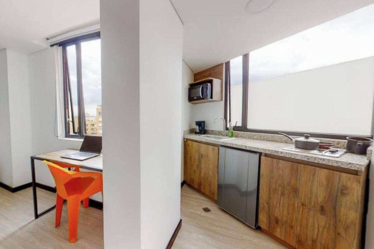 Un appartement compact doté d’une kitchenette, d’un coin repas avec une chaise et d’une fenêtre offrant une vue sur la ville.