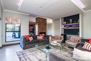 Una sala de estar moderna con chimenea, sofás, una mesa de centro y una estantería.