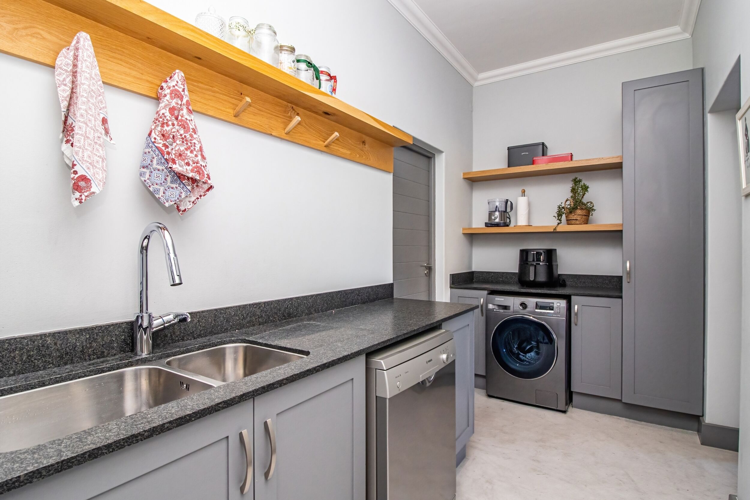 Cozinha moderna com bancada de granito, pia de aço inoxidável e máquina de lavar louça embutida.