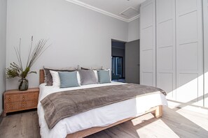 Ein Schlafzimmer mit einem Bett, einem Nachttisch und einer Topfpflanze.
