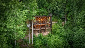 A multi-level wooden cabin with balconies, surrounded by dense forest. - The Day Hike - Pet Friendly | Mountain View | Outdoor Fireplace | Oversized Deck (Blue Ridge)