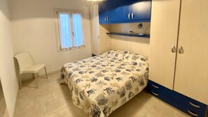 Ein Schlafzimmer mit Bett, Sessel, Schreibtisch und Kleiderschrank.