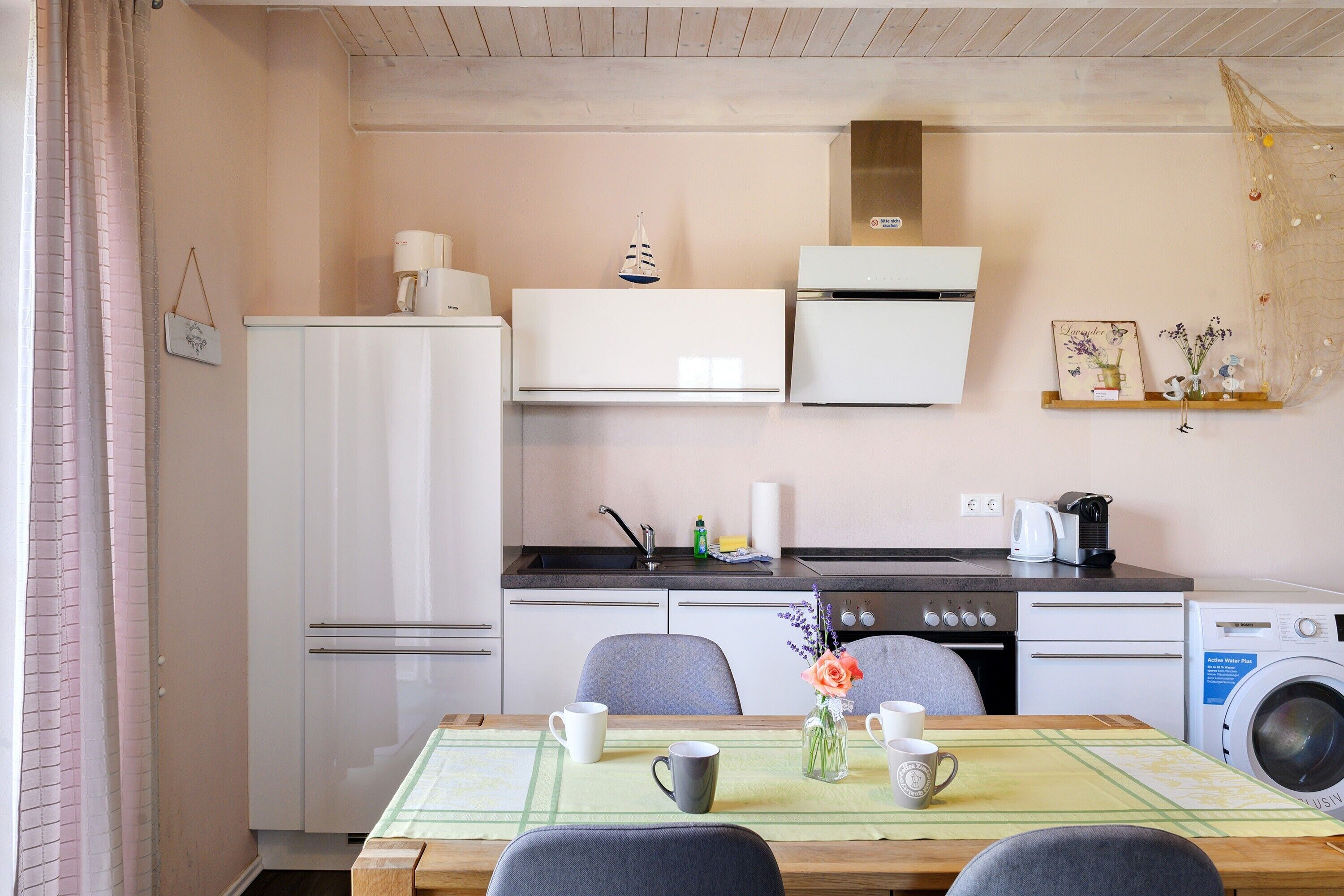 Une cuisine compacte équipée d’un réfrigérateur, d’une cuisinière, d’un four à micro-ondes et d’un lave-linge.