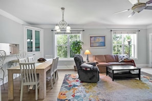 A spacious living room with a dining area, a sofa, a coffee table, and a chandelier. - 3 bedroom two bath with a community pool. Sleeps 7. (Saint Simons Island)