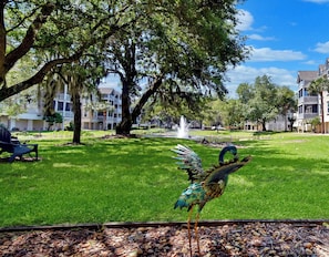 A bird sculpture in a park with a fountain, surrounded by lush greenery and multi-story buildings. - 3 bedroom two bath with a community pool. Sleeps 7. (Saint Simons Island)