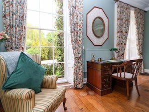 Une pièce avec une grande fenêtre, un bureau avec des tiroirs, une chaise et un canapé à rayures.