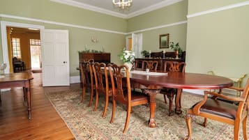 A dining room with a large wooden table, matching chairs, a chandelier, and a patterned rug.
