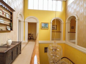 A hallway with a wooden bench, a chandelier, and a door leading to another room.