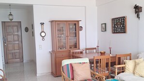 Un salon comprenant une table à manger, des chaises, un canapé, un meuble et une horloge murale.