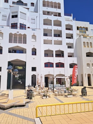 Ein mehrstöckiges Hotel mit Balkonen, Außenbestuhlung und einer Flagge.