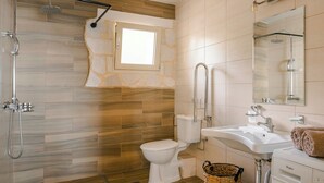 Ein Badezimmer mit Dusche, Toilette, Waschbecken und einem großen Spiegel.