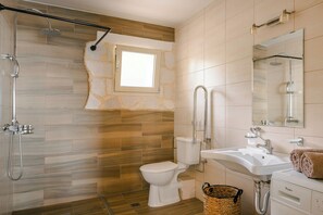 A bathroom with a shower, toilet, sink, and a large mirror. - Villa Ainos of Lithos Villas (Vlachata)