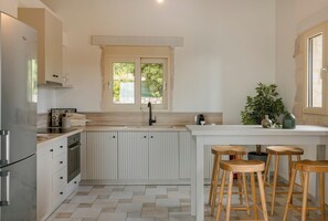 A kitchen with a central island, a double sink, and wooden stools. - Villa Ainos of Lithos Villas (Vlachata)