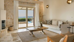 Ein geräumiges Wohnzimmer mit Steinwand, einer Couch, einem Couchtisch und Meerblick.