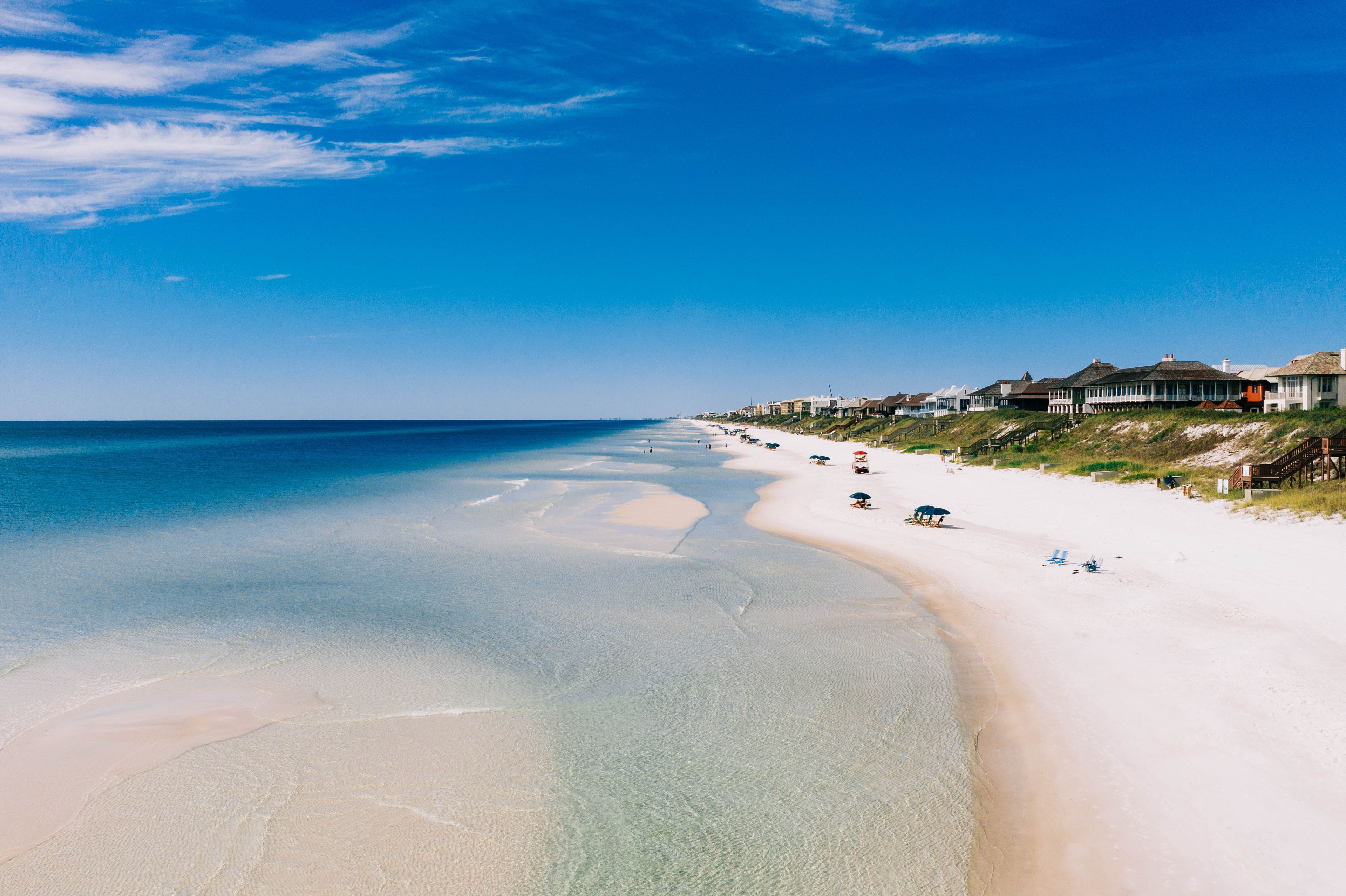 Une plage aux eaux cristallines, un rivage sablonneux et des propriétés situées en bord de mer.