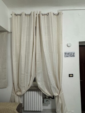 Een kamer met een bed, een radiator en een lichtschakelaar aan de muur.