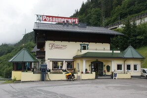 Un restaurante llamado 'Posaunerwirt' con un edificio de techo verde, una pequeña estructura adosada también con techo verde y una motocicleta estacionada.