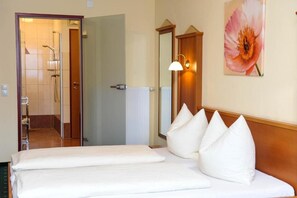 Una habitación de hotel con cama, ducha y un cuadro en la pared.