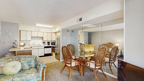 A compact living space with a kitchenette, dining area, and a large mirror. - Outrigger 110 (Ocean City)