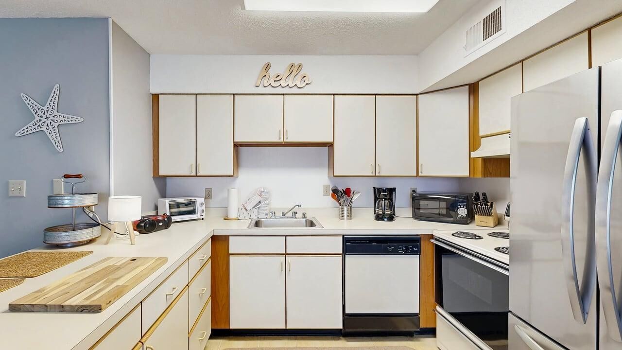 Une cuisine moderne avec des meubles blancs, un lave-vaisselle, une cuisinière et un réfrigérateur.