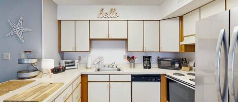 Une cuisine moderne avec des meubles blancs, un lave-vaisselle, une cuisinière et un réfrigérateur.