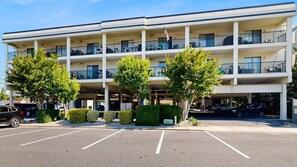 A multi-story hotel with balconies, a parking lot, and a flag. - Outrigger 110 (Ocean City)