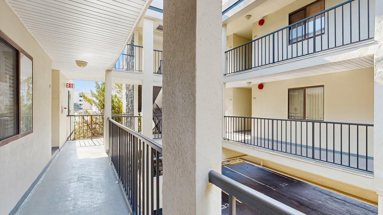A multi-story building with balconies, a visible exit sign, and a clear sky.