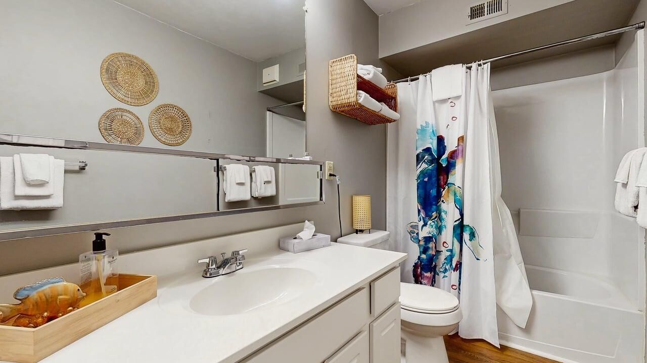 A modern bathroom with a large mirror, white sink, and shower curtain.