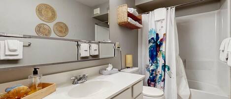 A modern bathroom with a large mirror, white sink, and shower curtain.