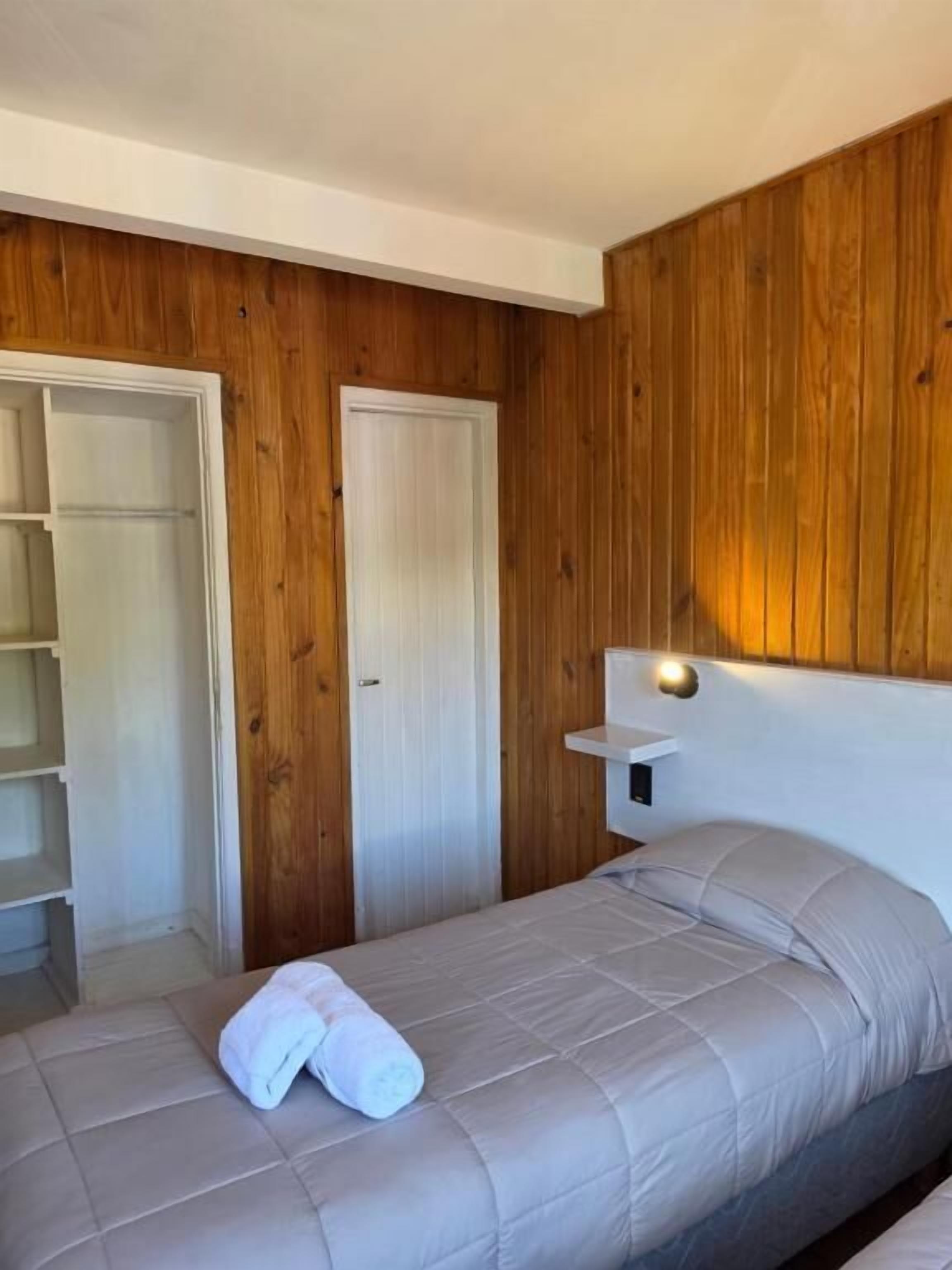 Un dormitorio con cama, armario y mesita de noche.