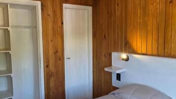 Un dormitorio con cama, armario y mesita de noche.