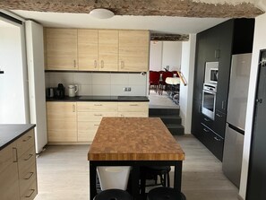 A modern kitchen with wooden cabinets, a central island, and built-in appliances. - Maison Lara with natural swimming pool in the heart of the Cathar countryside 7 people (Saint-Ferriol)