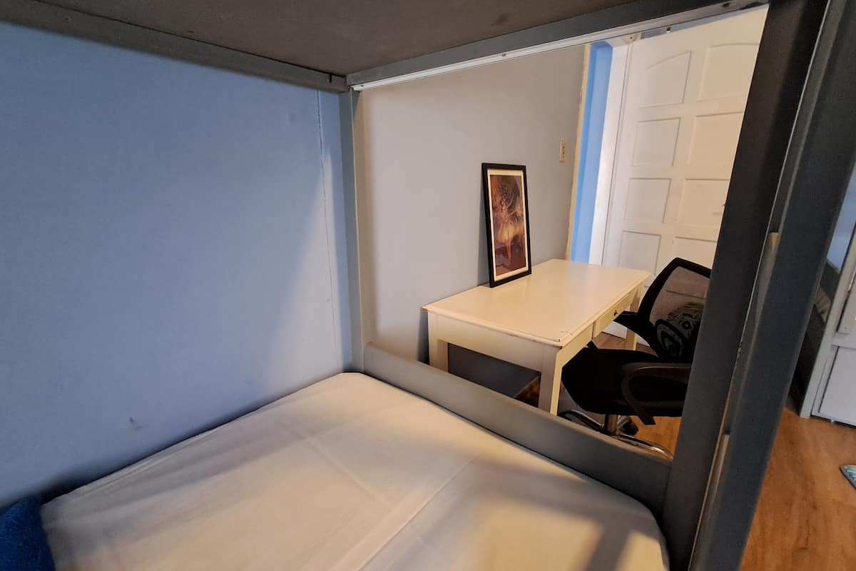 Una habitación pequeña con cama, un escritorio y una silla.