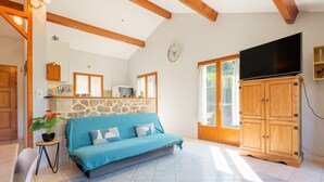Un salon avec un canapé, des meubles en bois, une télévision et un mur en pierre.