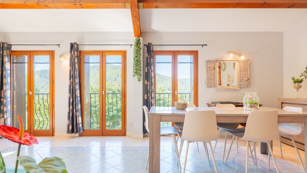 Un espace repas comprenant une table, des chaises et une vue dégagée grâce à de grandes fenêtres.